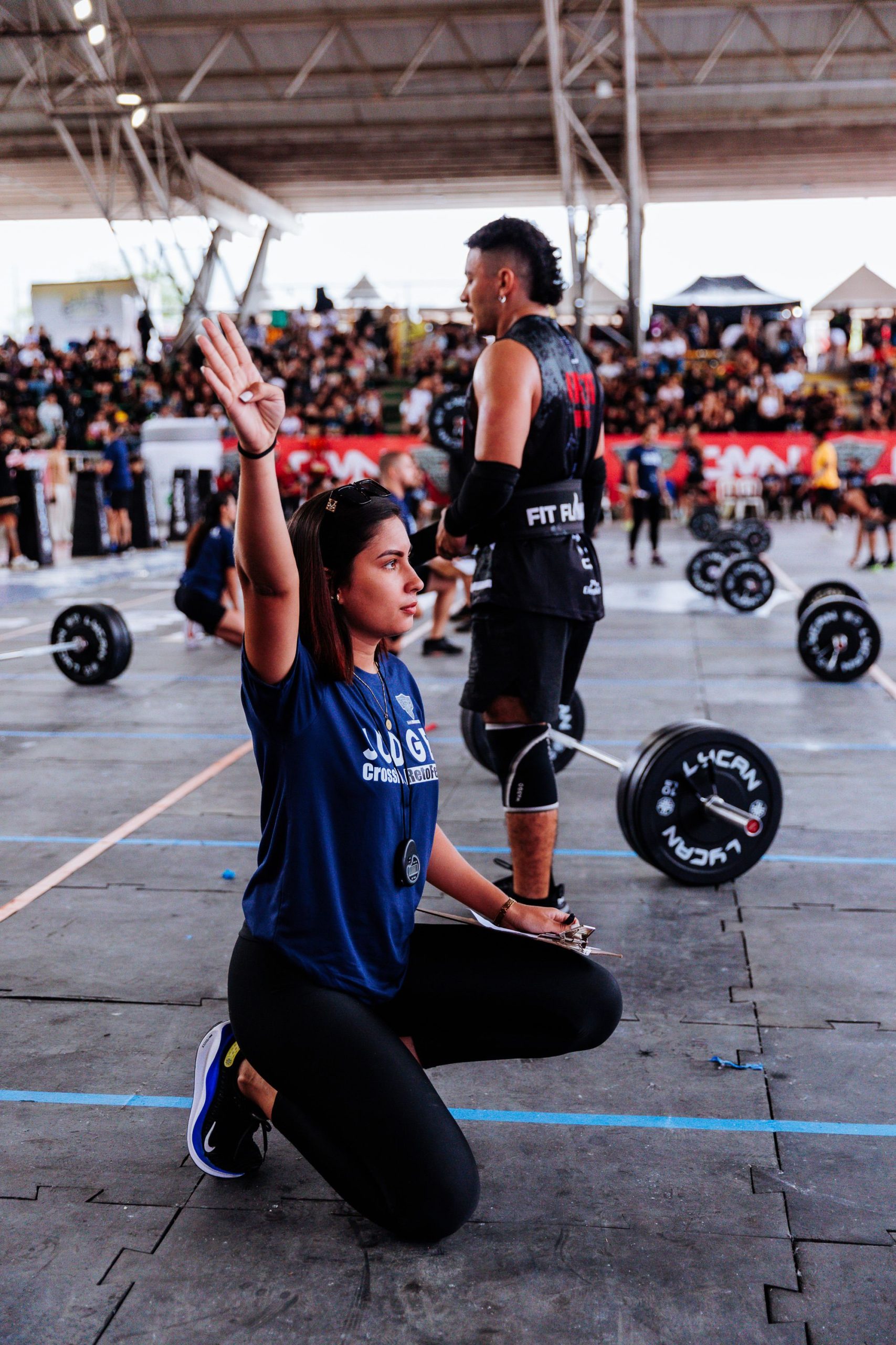 CrossFit competition athlete lifting weights as a judge oversees the event