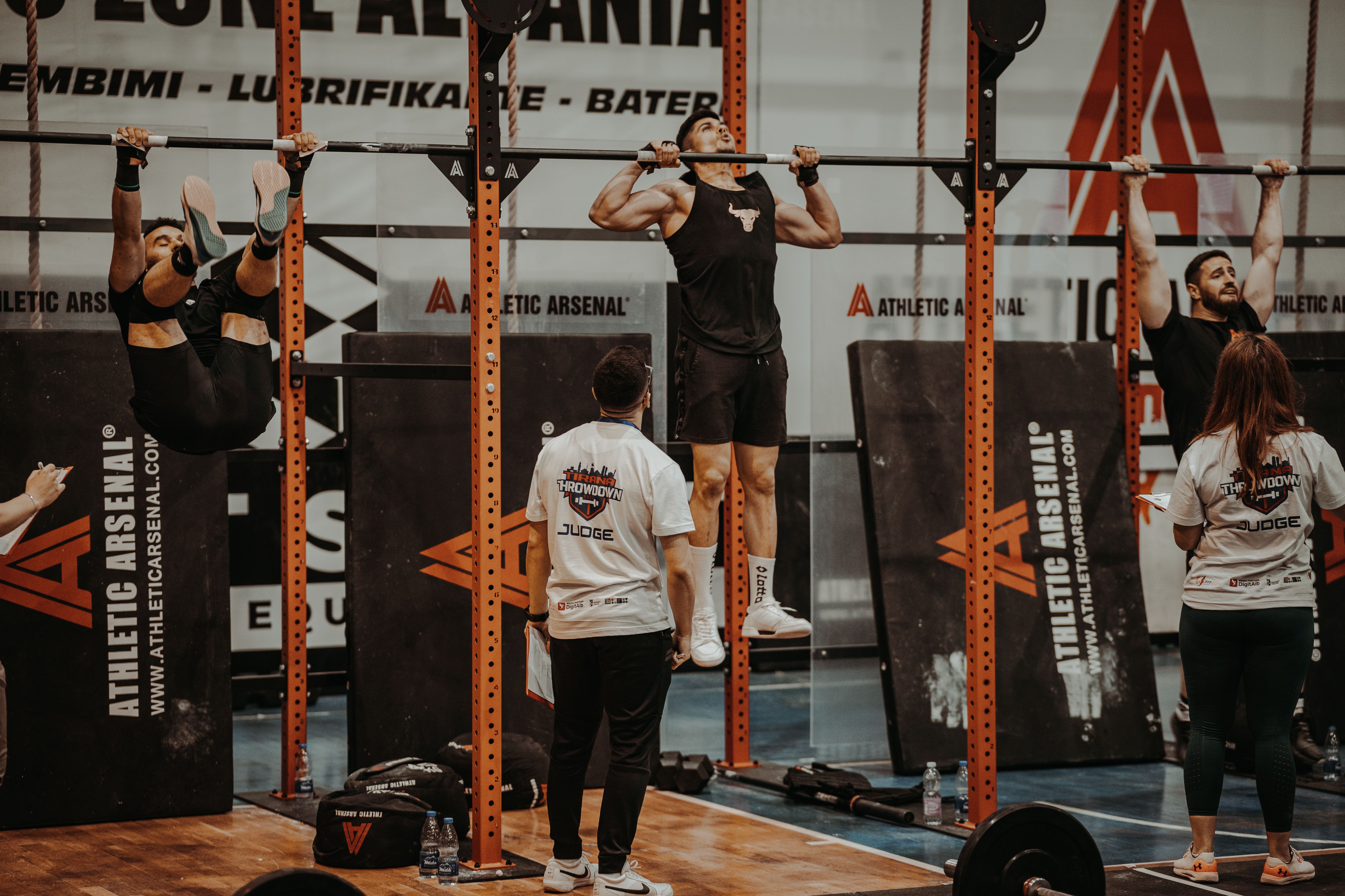 Athletes performing pull-ups in a judged CrossFit competition showcasing functional fitness