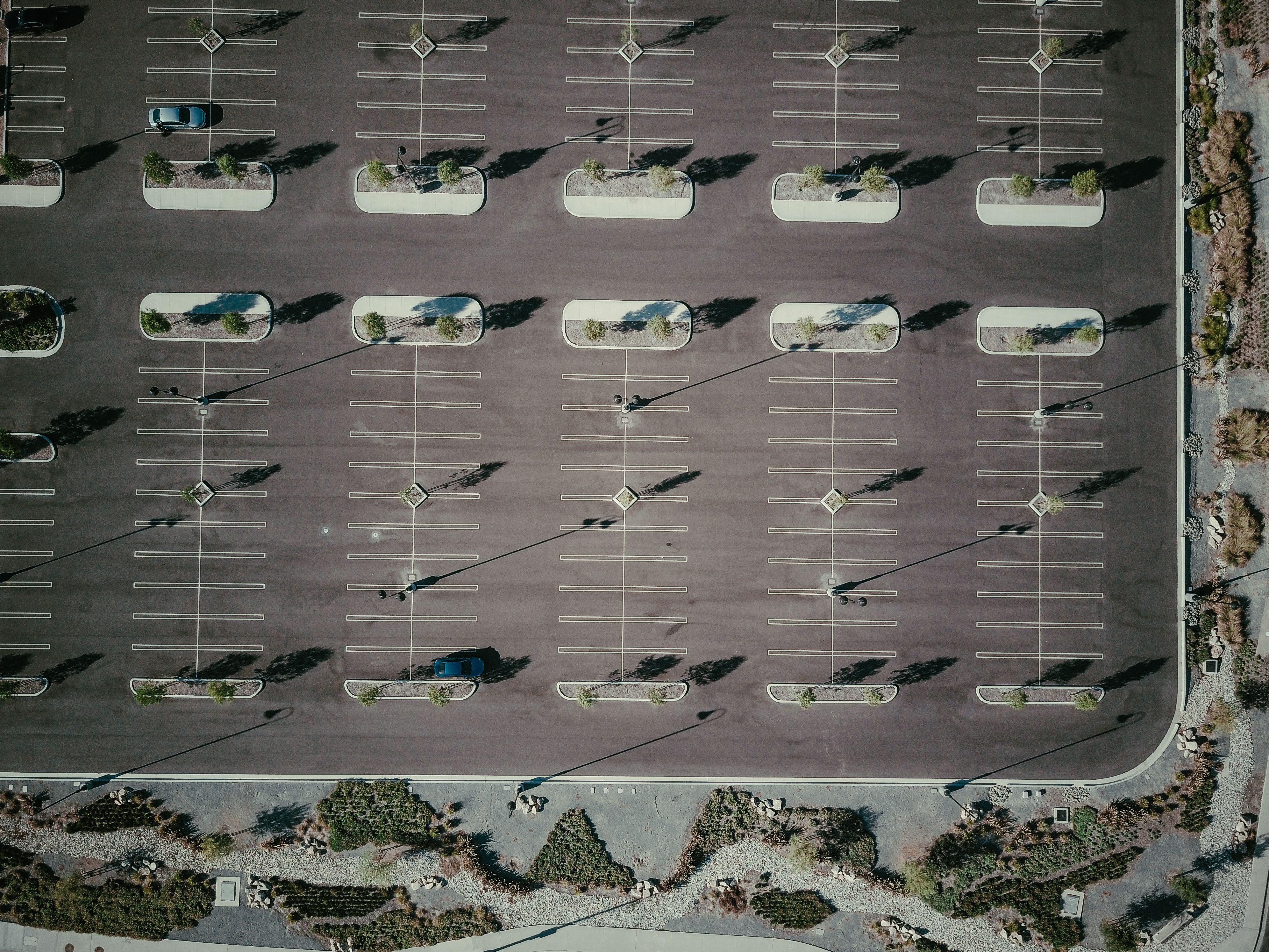 Drone aerial view of an empty commercial parking lot with trees and shadows