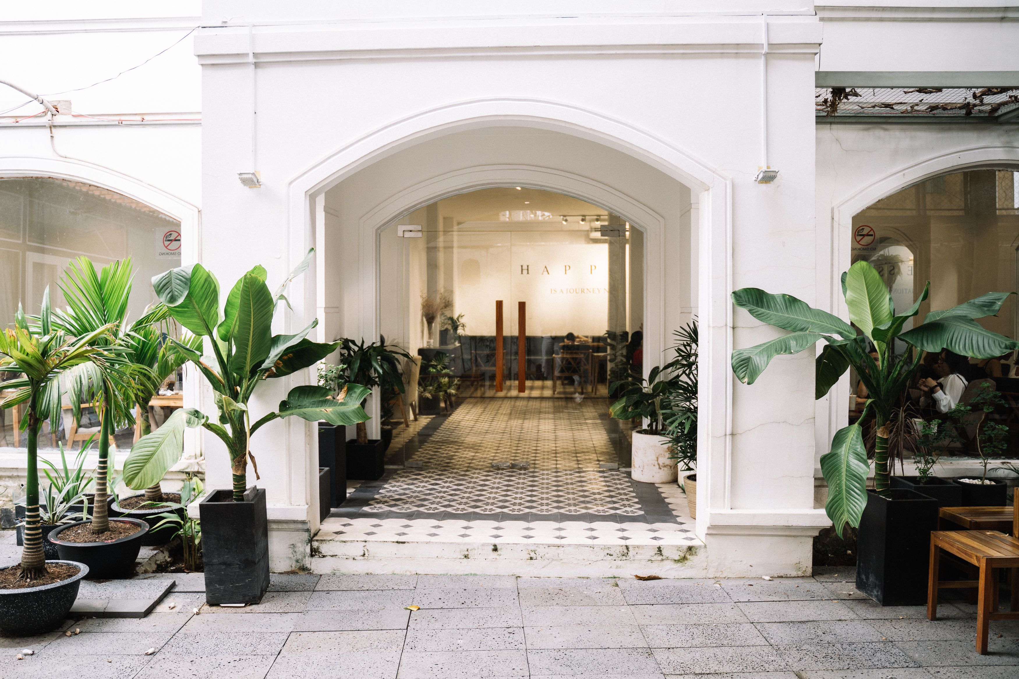 Business entrance framed by lush plants and a stylish arched doorway